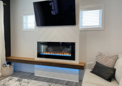 modern basement living area with an electric fireplace feature and a mounted TV by Axium Interiors Saskatoon.