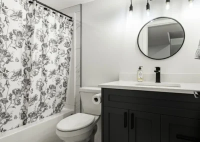 modern bathroom vanity with black cabinetry and lighting feature by Saskatoon basement developer Axium Interiors